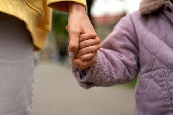 An adult holding a child's hand, symbolizing trust, care, and support in foster care.