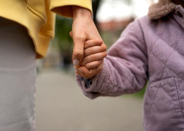 An adult holding a child's hand, symbolizing trust, care, and support in foster care.